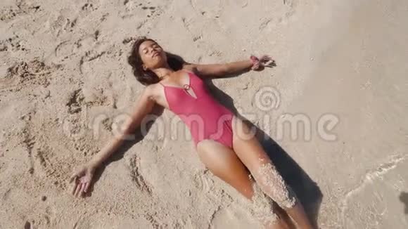 穿着泳衣的亚洲女孩在沙滩上晒日光浴眼睛紧闭视频的预览图