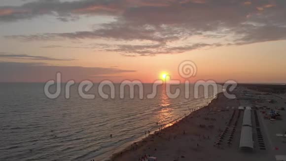 鸟瞰美丽的日落越过大海和沙滩人们在海浪中游泳视频的预览图