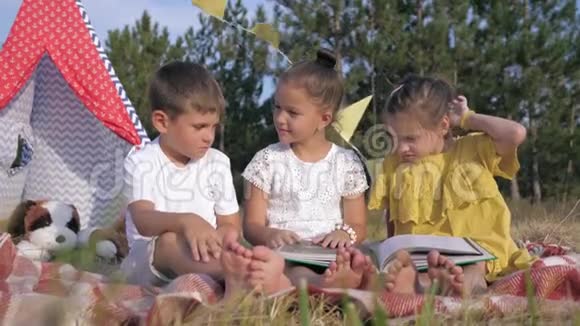 面部表情有趣的孩子在书中阅读有趣的故事并在森林野餐时展示有趣的面孔视频的预览图