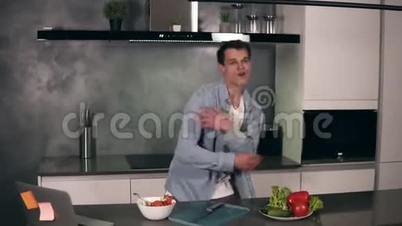 活跃的白种人年轻人站在现代灰色厨房里享受滑稽的舞蹈快乐的时髦独立男人视频的预览图