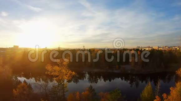 日落时分飞过一个城市池塘四周是黄色的秋树视频的预览图