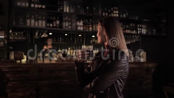 时尚的咖啡馆一个漂亮的女孩在一个大酒吧里手里拿着一杯美味的饮料看着酒保工作然后喝酒视频的预览图