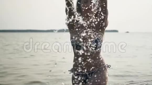 一个苗条的年轻女子在炎热的夏天享受大海慢动作视频的预览图