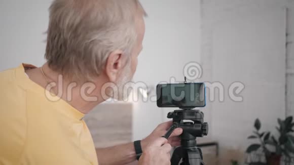 祖父和技术年长的男性博主很有影响力准备用他的智能手机录制vlog设置视频的预览图