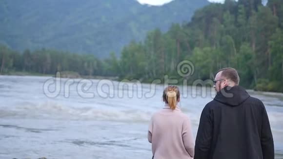 一对年轻的恋人拥抱在阿尔泰山和山河的背景上慢动作视频的预览图