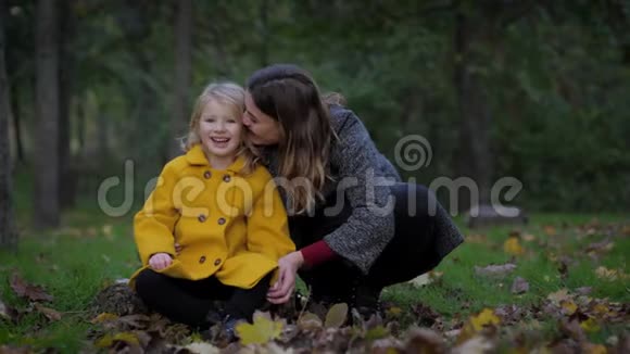 迷人的年轻女子和可爱的微笑的女孩子正在放松在秋天的季节在草地上的秋天公园嘘视频的预览图
