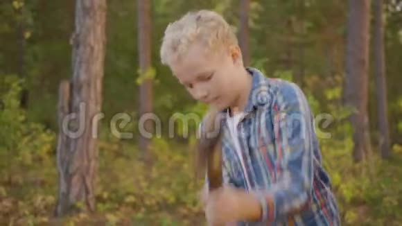 少年男孩在夏天的森林里用斧头砍木头在旅游远足旅游男孩用斧头砍木头视频的预览图