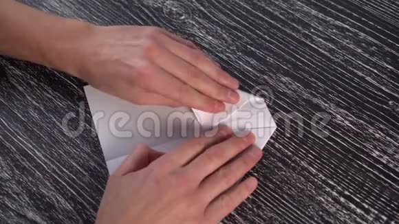 在黑色纹理木桌上组装白纸折纸飞机视频的预览图