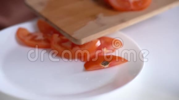 女人用烹饪刀把切好的西红柿放在盘子里特写视频的预览图