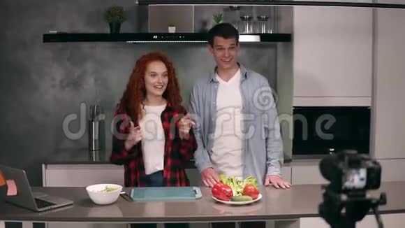 年轻夫妇一起休闲烹饪在阁楼的灰色厨房里相机录制视频食物博客视频的预览图