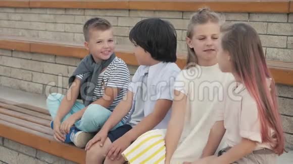 两个男孩和两个女孩坐在长凳上聊天视频的预览图