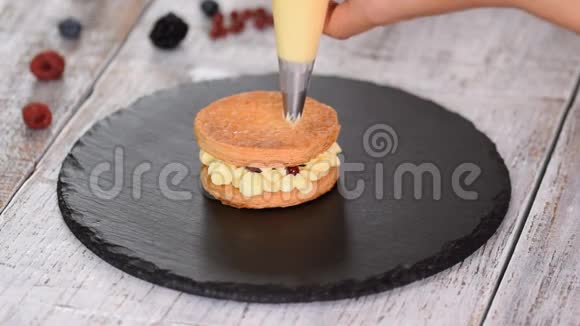 糕点厨师用奶油和浆果制作法国米尔菲耶法式甜点牛奶酥皮点心和奶油冻视频的预览图