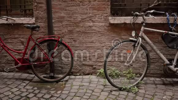 两辆旧的经典自行车红白相间停在古老的砖墙附近视频的预览图