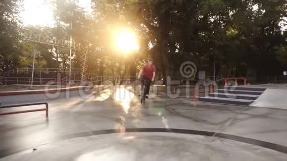 在美丽的夏天或秋天年轻的bmx自行车手从阳光明媚的城市滑冰公园的自行车座位上骑车跳起来酷酷视频的预览图