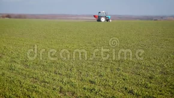 拖拉机在绿色的田野里传播人工肥料农民用氮肥和钾肥耕地视频的预览图