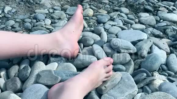 一个孩子的腿在卵石滩上一个不知名的孩子坐在海边玩石头视频的预览图