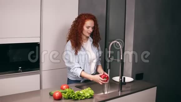 迷人的红头女人在厨房里洗红辣椒黄瓜和西红柿然后把它们放在盘子里自制食物视频的预览图