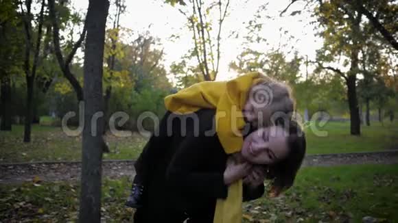 在秋季的家庭散步期间英俊的小女孩和他的母亲在秋天的公园里玩得很开心视频的预览图