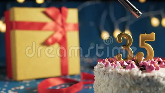 白色生日蛋糕数字35金色蜡烛燃烧的打火机蓝色背景灯和礼品黄色盒子捆绑视频的预览图