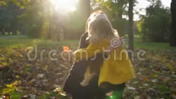 无忧无虑的孩子快乐的微笑的女孩子在秋天的公园散步时紧紧地拥抱她慈爱的母亲视频的预览图