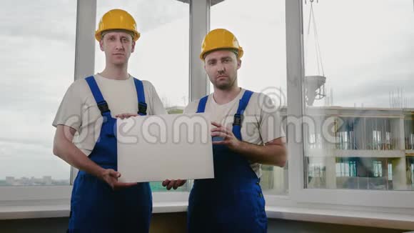 两个悲伤的建筑工人拿着木板或海报找工作视频的预览图