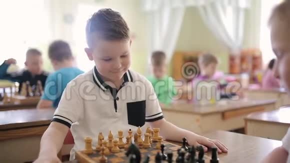 一个穿白色T恤的男孩正在下棋孩子们在幼儿园里玩教育游戏视频的预览图
