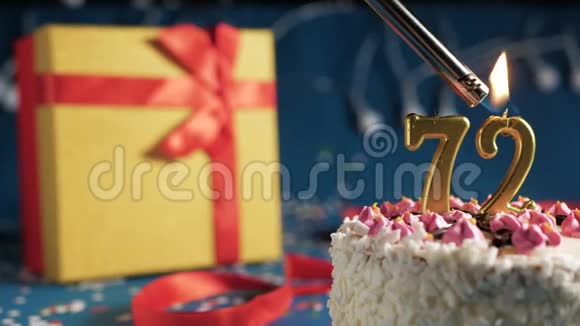 白色生日蛋糕72支金色蜡烛用打火机点着蓝色背景配灯黄色礼品盒用红色系起来视频的预览图
