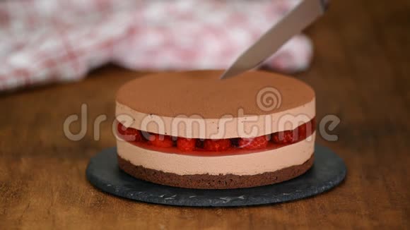 女人手用覆盆子果冻切美味的巧克力慕斯蛋糕视频的预览图