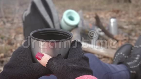 坐在森林里的树上喝着热饮料热水瓶里的茶休息的女孩视频的预览图