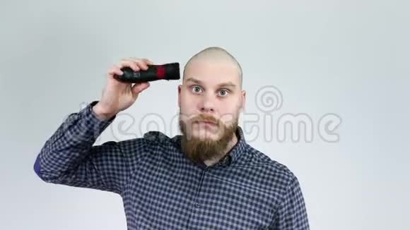 留胡子的家伙用剪发器剃头看在倒影里视频的预览图