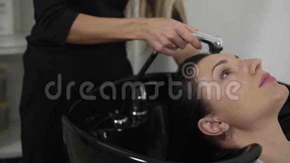 美容工作室洗黑发女人的头发化妆和美容院上紧理发师的手在头上洗头视频的预览图