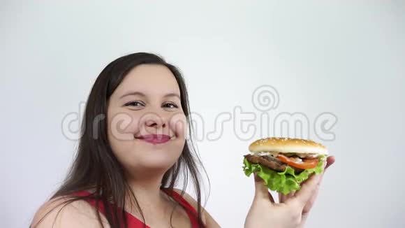 一个肥胖的年轻女人吃汉堡包感受快乐快餐垃圾视频的预览图