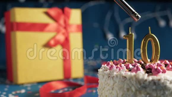 白色生日蛋糕数字10金蜡烛点燃打火机蓝色背景灯和礼品黄盒子捆绑视频的预览图