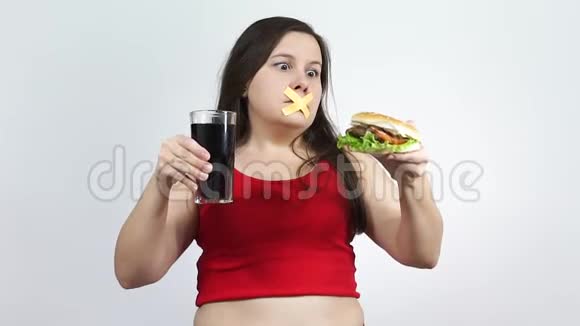 年轻的女人嘴上有胶带阻止她吃垃圾食品视频的预览图