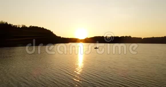 日落时分垂钓者在湖边的船上钓鱼视频的预览图