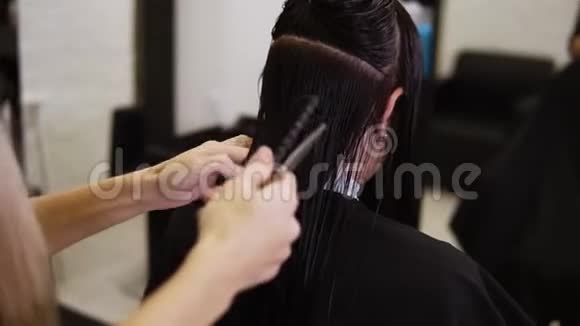 在美容院实习的发型师会把湿发梳成时尚的发型并加以改变视频的预览图