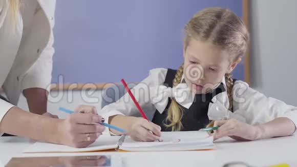 白种人迷人的女学生用红色铅笔写的肖像而不可辨认的老师站在她旁边视频的预览图
