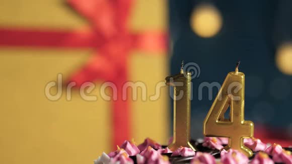 生日蛋糕14号金色蜡烛用打火机点燃蓝色背景礼品黄色盒子用红丝带系好视频的预览图