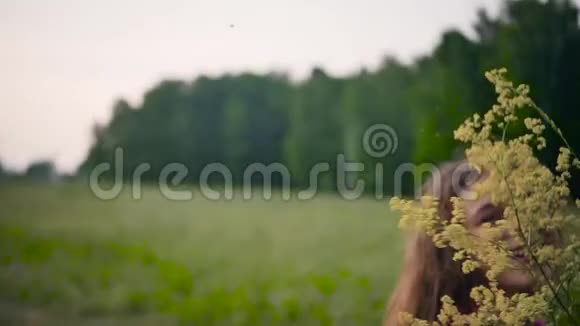 一个金发碧眼的年轻姑娘手里拿着黄色手里拿着黄色的野花动作缓慢视频的预览图