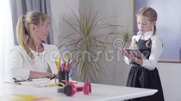 镜头慢慢地接近穿着校服的白种人女孩对着坐在桌边的中年教师视频的预览图