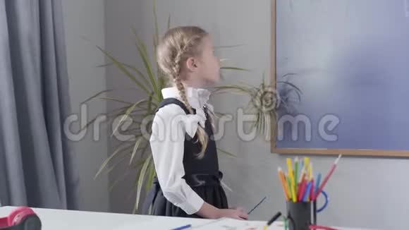 可爱的白种人女学生从黑板上转过身来伸出大拇指快乐的孩子在家学习教育视频的预览图