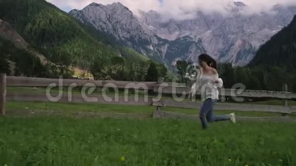 乡村女孩正在阿尔卑斯山牧场的农场里奔跑牧场是奶牛视频的预览图