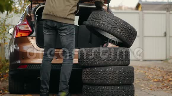 一个人把冬天的轮胎放在汽车的后备箱里视频的预览图