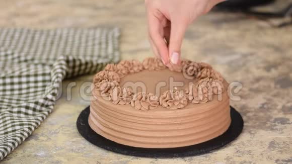 在巧克力海绵蛋糕的奶油上涂上果仁面包师用坚果装饰巧克力蛋糕视频的预览图