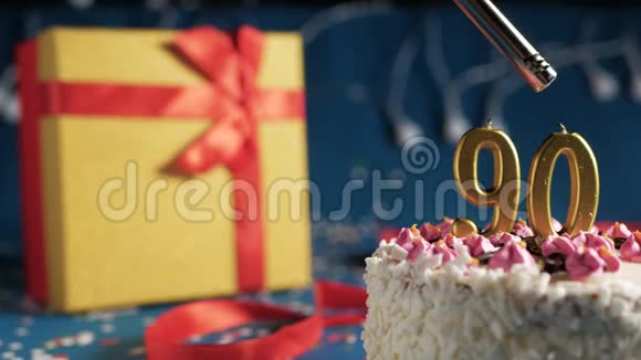 白色生日蛋糕数字90金色蜡烛点燃打火机蓝色背景灯和礼品黄色盒子与红色捆绑视频的预览图