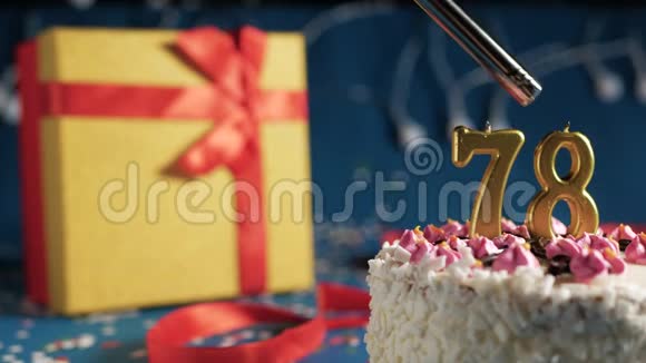 白色生日蛋糕数字78金色蜡烛点燃打火机蓝色背景灯和礼品黄色盒子与红色捆绑视频的预览图