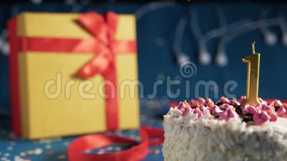 白色生日蛋糕1号金色蜡烛由打火机点燃蓝色背景灯和礼品黄色盒子系好视频的预览图