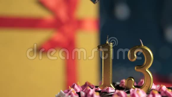 生日蛋糕13号金色蜡烛用打火机点燃蓝色背景礼品黄色盒子用红丝带系好视频的预览图