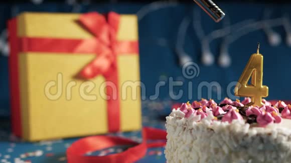 白色生日蛋糕4号金烛由打火机点燃蓝色背景与灯和礼品黄色盒子捆绑视频的预览图