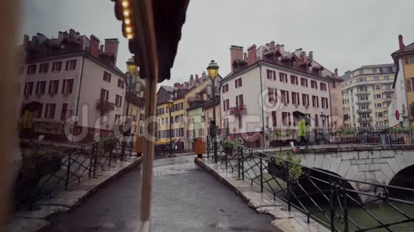 穿着亮黄色外套带着雨伞的女人在雨天通过运河穿过大桥法国安纳西视频的预览图